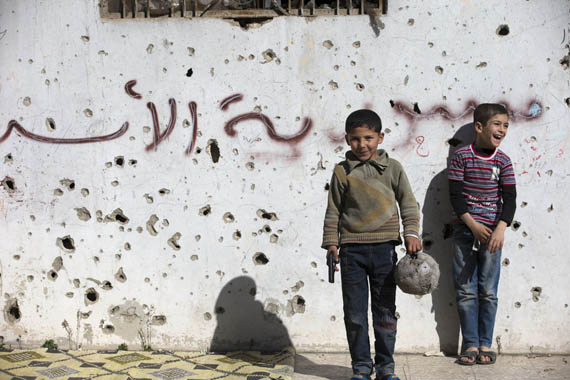 Мальчики на фоне граффити: «Сирия аль‑Асад». Хомс, Сирия. 26 февраля 2016. AP Photo/Hassan Ammar