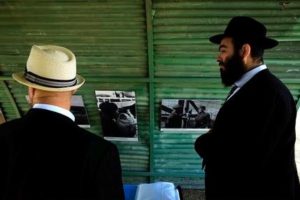 Jewish men look at the vintage photos of the British camp on a recreation of a semi-circular, corrugated iron hut that housed detainees, at the Cypriot military camp in capital Nicosia, on Wednesday, Nov. 9, 2016. Dozens of people born to Jewish refugees interned in Cyprus after World War II have marked the 70th anniversary of the start of such detentions at a ceremony on the east Mediterranean island. A memorial commemorating the event was unveiled at a Cypriot army camp that formerly housed a British military hospital where hundreds of Jewish infants were born. (AP Photo/Petros Karadjias)